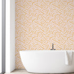 Modern bathroom with a white freestanding bathtub against a wall with a gold leaf pattern.