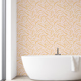 Modern bathroom with a white freestanding bathtub against a wall with a gold leaf pattern.