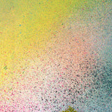 A vase of flowers stands in front of a wall covered in an abstract ombré paint splatter print in pink, yellow, blue and green.