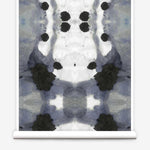 Partially unrolled wallpaper yardage in a watercolor ink blot print in charcoal, gray and white.