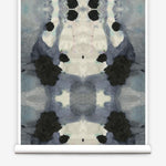 Partially unrolled wallpaper yardage in a watercolor ink blot print in charcoal, gray and tan.