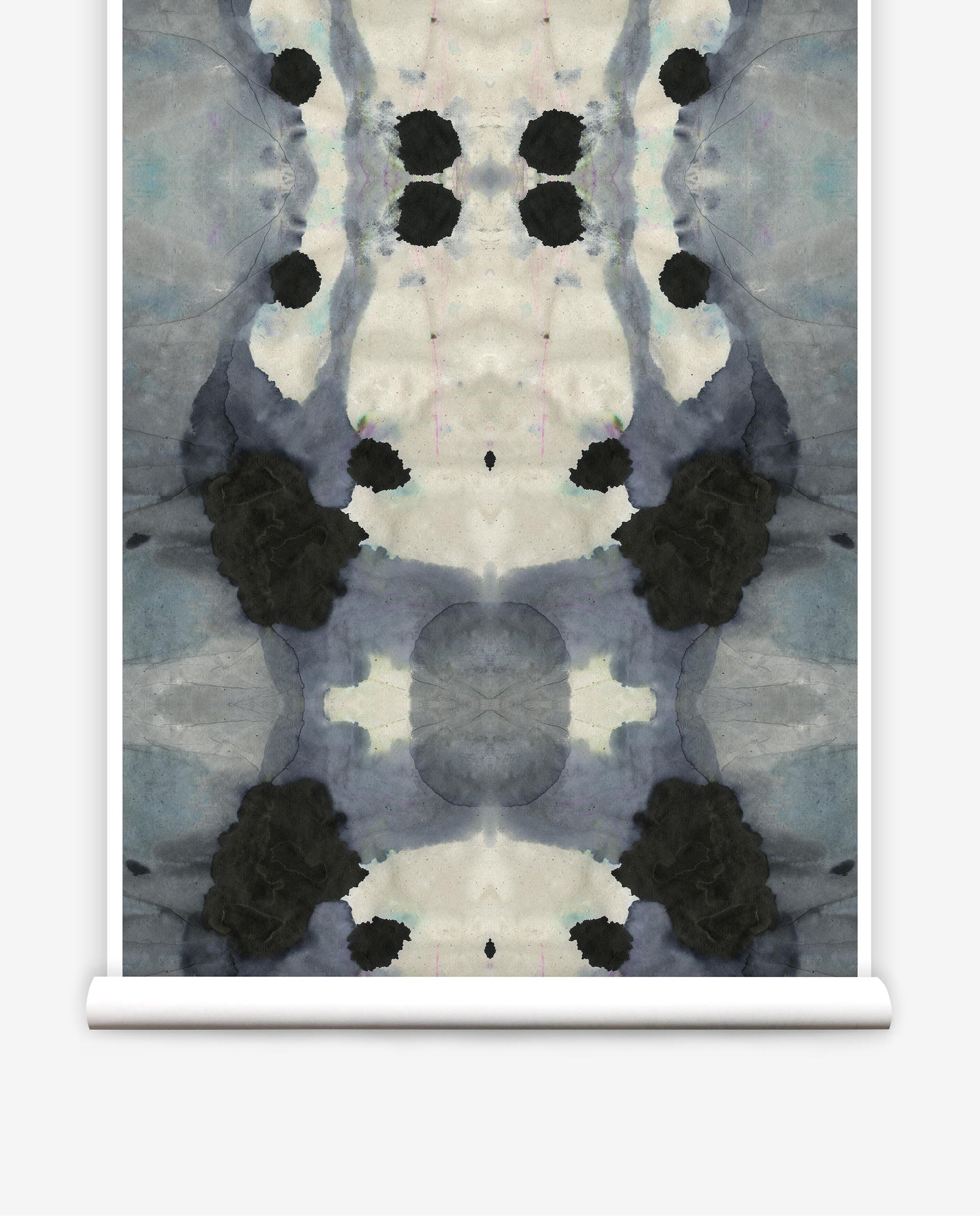 Partially unrolled wallpaper yardage in a watercolor ink blot print in charcoal, gray and tan.