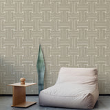 A plush chair and end table stand in front of a wall papered in a large-scale geometric print in tan and cream.