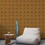 A plush chair and end table stand in front of a wall papered in a large-scale geometric print in gold and black.