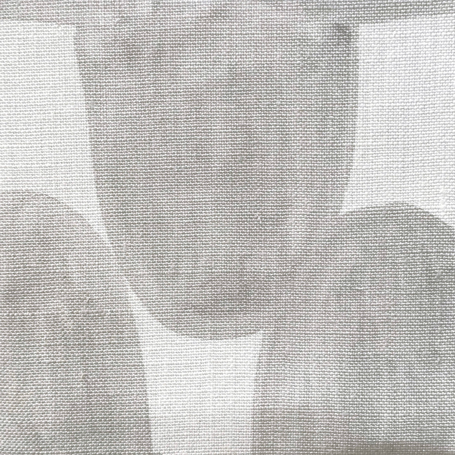 Close-up of fabric in an abstract scalloped print in gray on a white field.