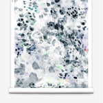 Partially unrolled wallpaper yardage in a watercolor paint blotch print in black, gray, blue, green and white.