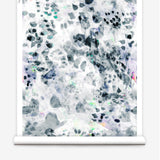 Partially unrolled wallpaper yardage in a watercolor paint blotch print in black, gray, blue, green and white.