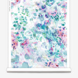 Partially unrolled wallpaper yardage in a watercolor paint blotch print in pink, green, turquoise and white.