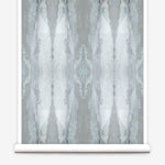 Partially unrolled wallpaper yardage in a watercolor textural print in shades of gray and blue-gray.