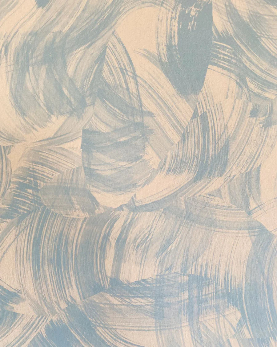 Detail of wallpaper in an abstract paint swatch print in light blue on a tan field.