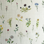 Detail of fabric in a painterly flower print in green and pastels on a cream field.