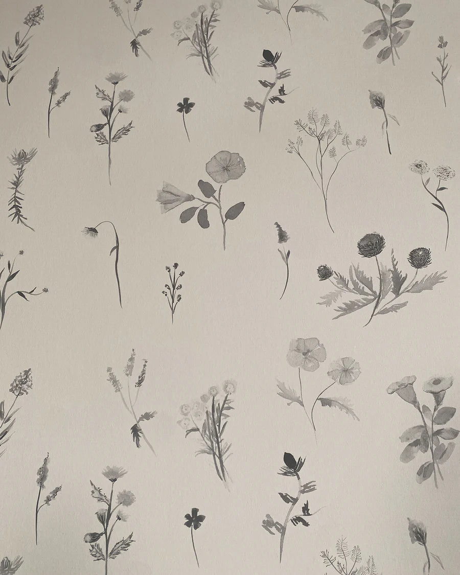 Detail of wallpaper in a painterly flower print in shades of gray on a cream field.