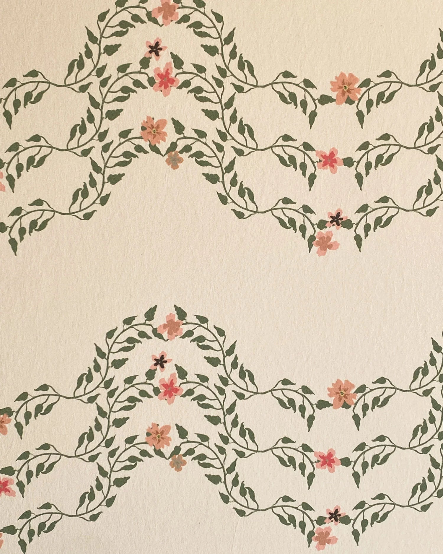 Detail of wallpaper in a curving floral stripe print in shades of orange and green on a cream field.