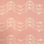 Detail of wallpaper in a curving floral stripe print in shades of cream on a pink field.