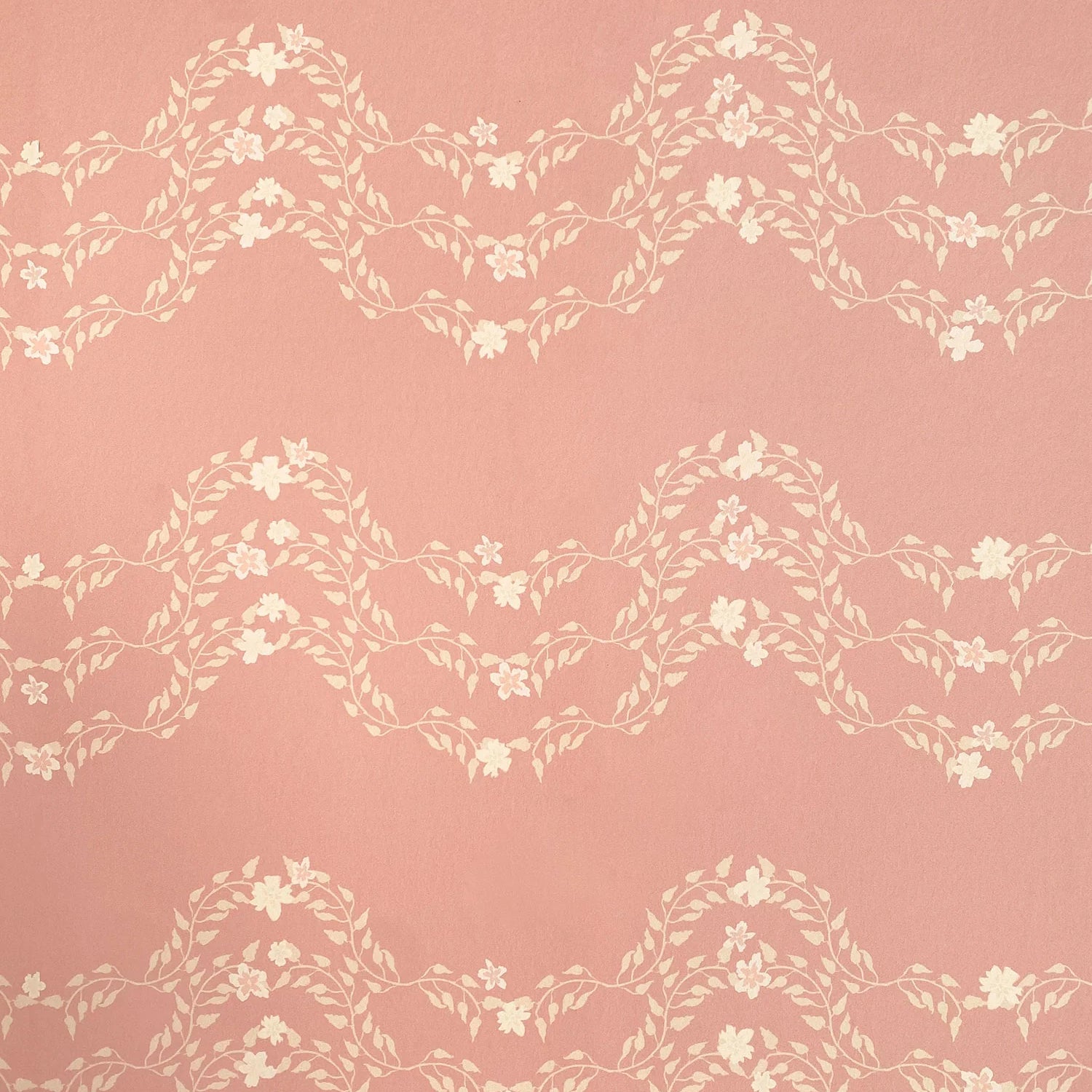 Detail of wallpaper in a curving floral stripe print in shades of cream on a pink field.