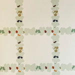 Detail of wallpaper in a floral grid print in cream, green and pink on a white field.