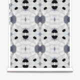Partially unrolled wallpaper yardage in a watercolor ink blot print in shades of charcoal and black on a greige field.