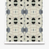 Partially unrolled wallpaper yardage in a watercolor ink blot print in shades of charcoal and black on a tan field.