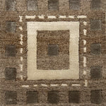 Handknotted rug in a decorative square design in sahdes of brown and cream on a taupe field