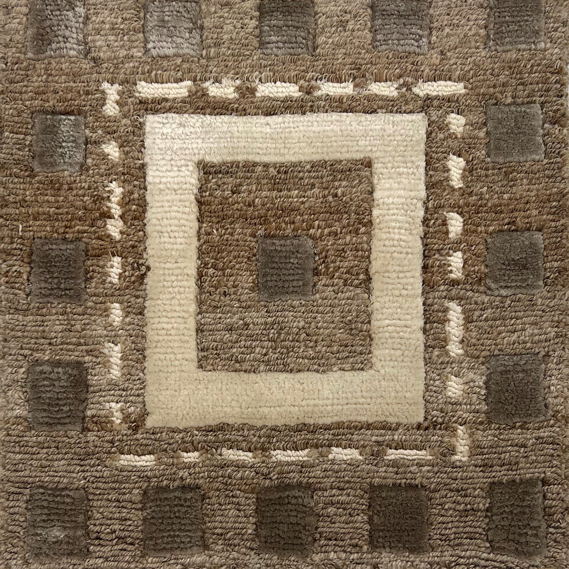 Handknotted rug in a decorative square design in sahdes of brown and cream on a taupe field