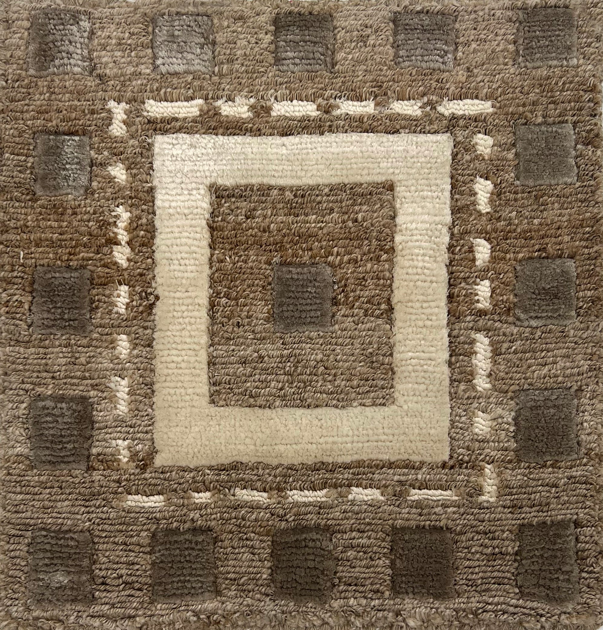 Handknotted rug in a decorative square design in sahdes of brown and cream on a taupe field