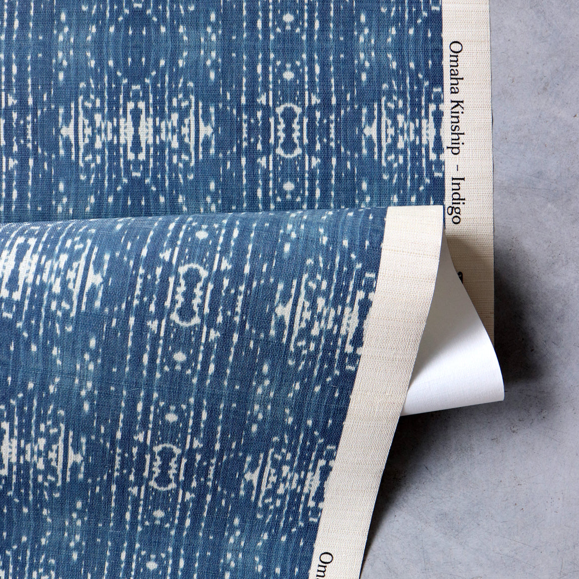 Draped yardage of printed grasscloth with ikat stripe design in blue and cream 