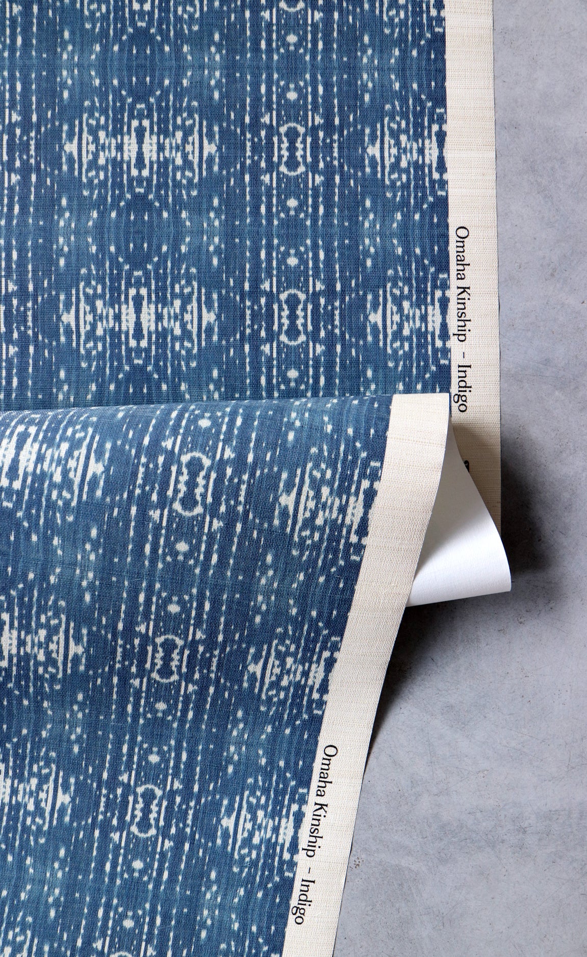 Draped yardage of printed grasscloth with ikat stripe design in blue and cream 