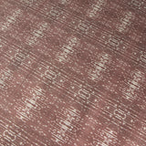 Close up of printed grasscloth with ikat stripe design in mauve red and cream 