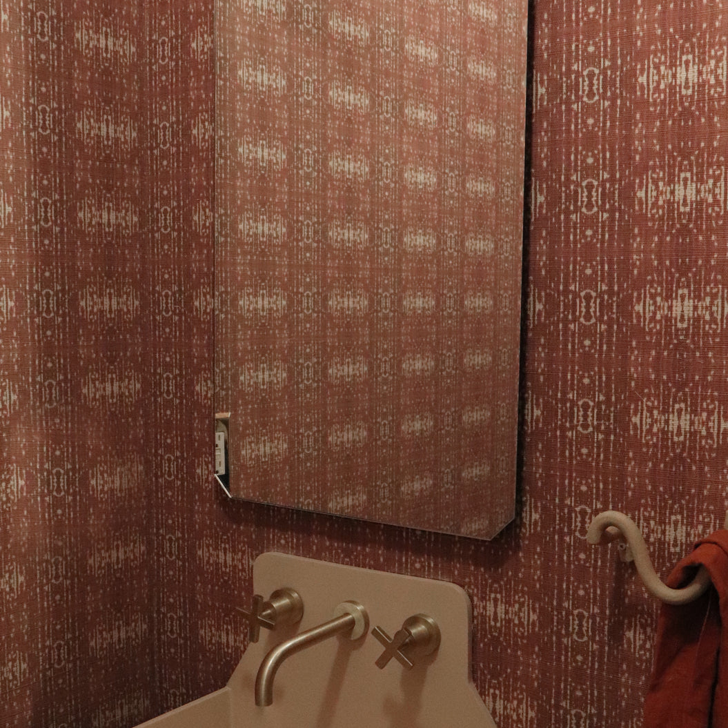 Powder room setting with printed grasscloth with ikat stripe design in mauve red and cream 