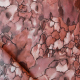 Detail draped fabric in a watercolor textural print in shades of red, gray and black.