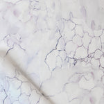 Detail draped fabric in a watercolor textural print in shades of white, purple and gray.