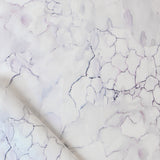 Detail draped fabric in a watercolor textural print in shades of white, purple and gray.