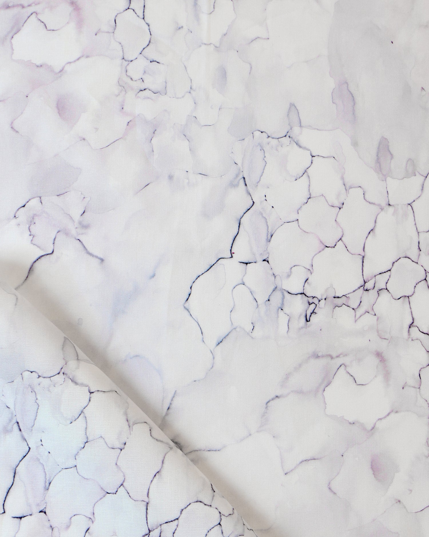 Detail draped fabric in a watercolor textural print in shades of white, purple and gray.
