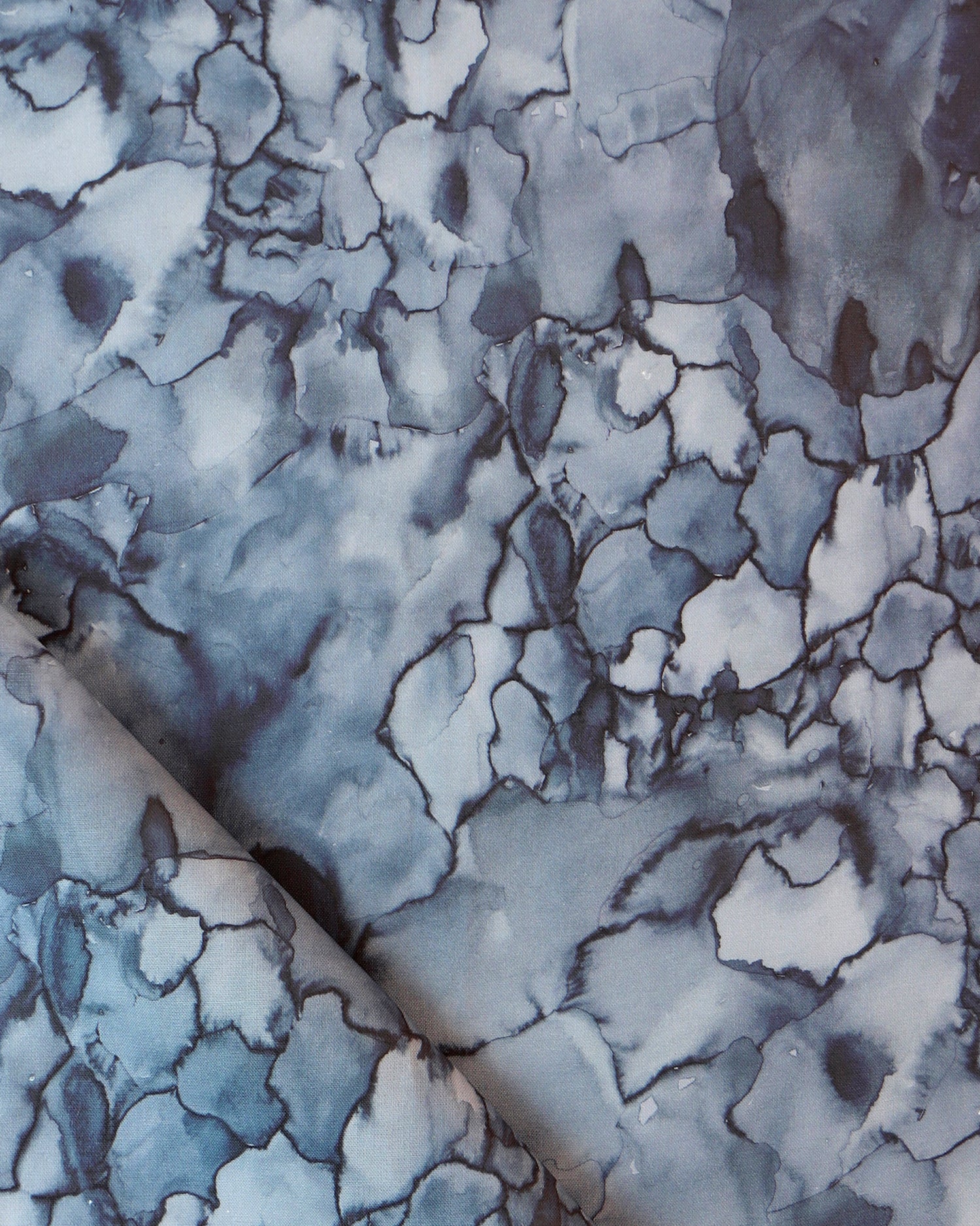 Detail draped fabric in a watercolor textural print in shades of blue, navy and black.