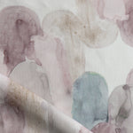 Detail of draped fabric in watercolor elongated pill pattern in soft purple, tan and teal on a white field.