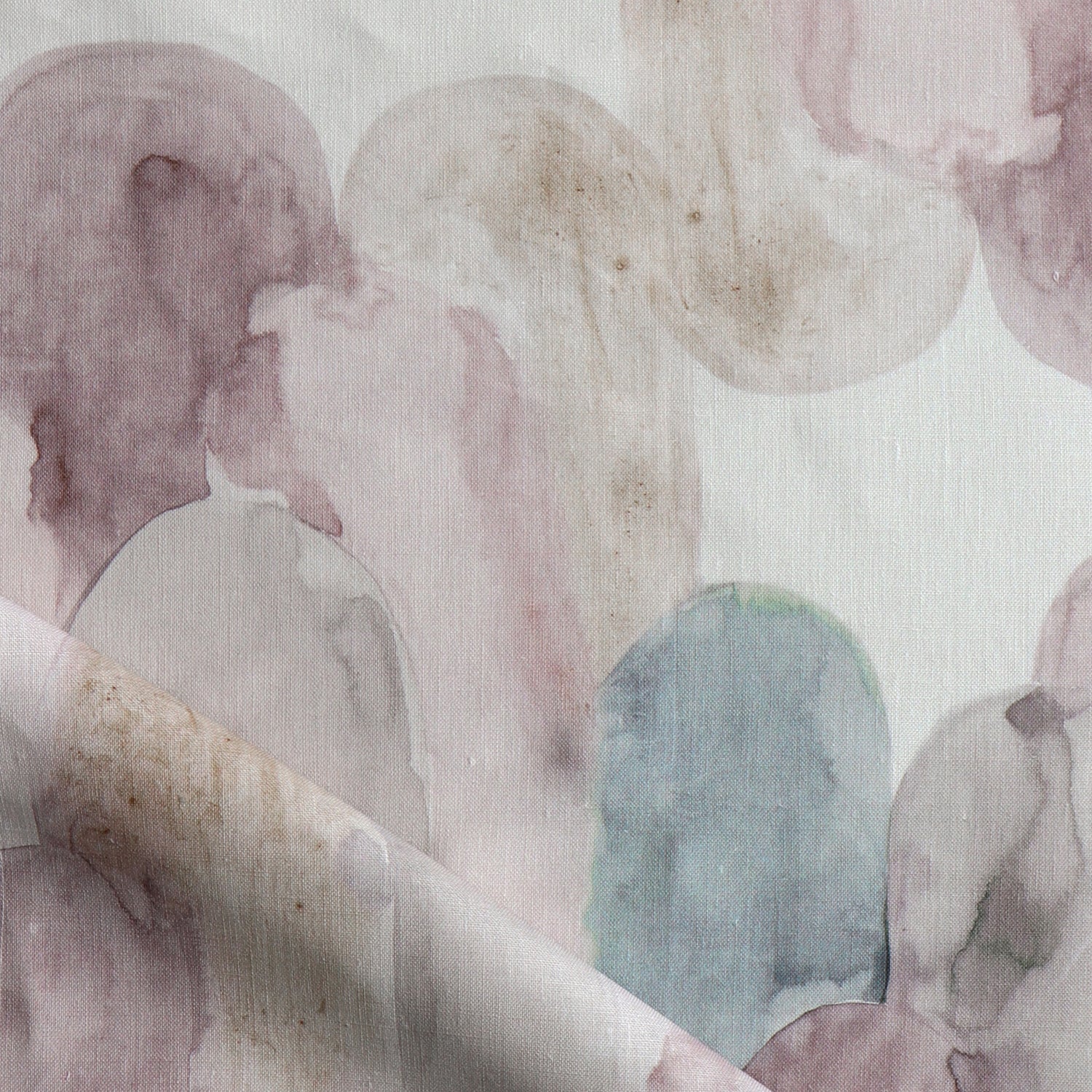 Detail of draped fabric in watercolor elongated pill pattern in soft purple, tan and teal on a white field.