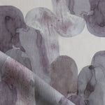 Detail of draped fabric in watercolor elongated pill pattern in moody purple on a white field.