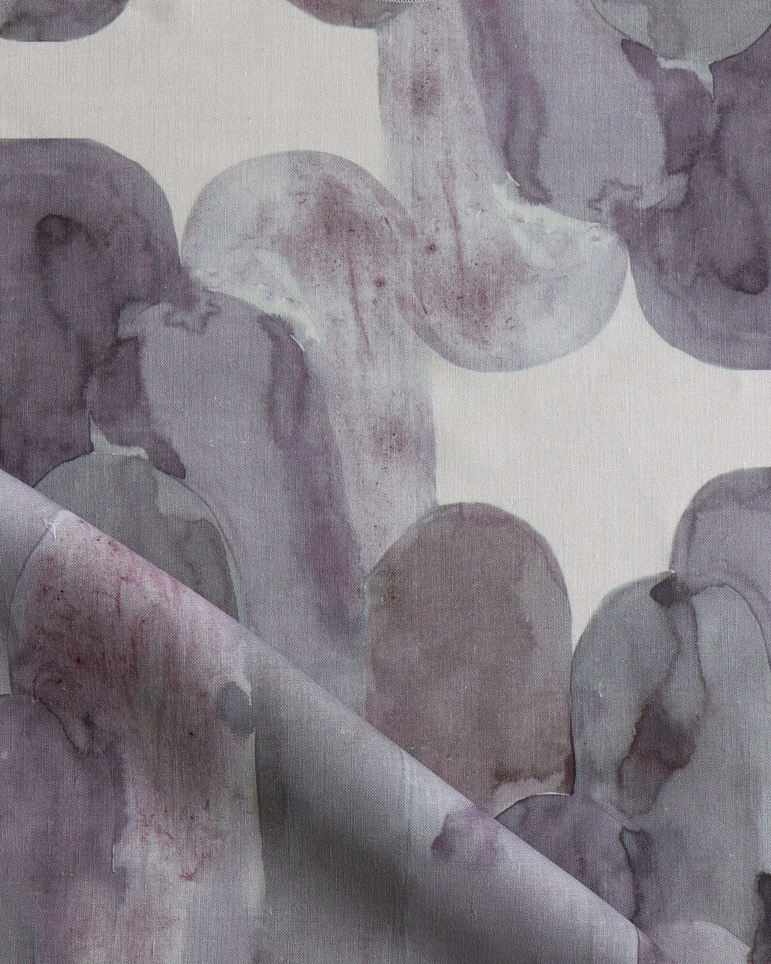 Detail of draped fabric in watercolor elongated pill pattern in moody purple on a white field.