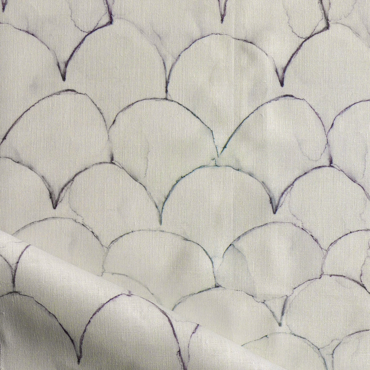 Detail of draped fabric in a watercolor linear scallop pattern in navy on a cream field. 
