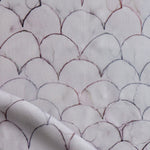 Detail of draped fabric in a watercolor linear scallop pattern in purple on a lilac field. 