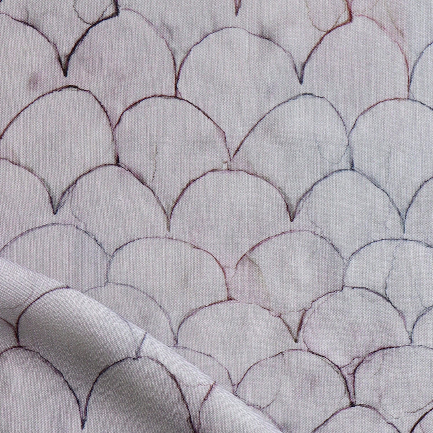 Detail of draped fabric in a watercolor linear scallop pattern in purple on a lilac field. 