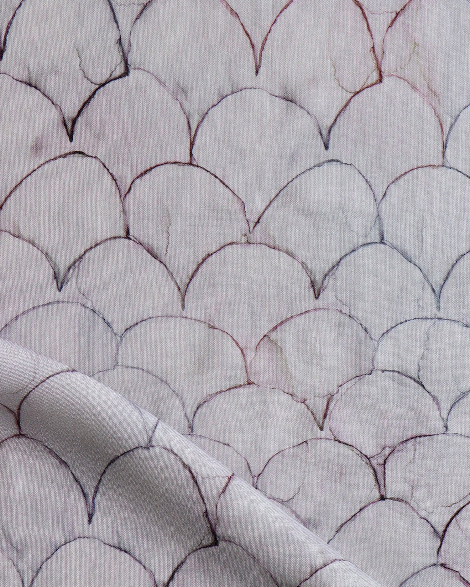 Detail of draped fabric in a watercolor linear scallop pattern in purple on a lilac field. 