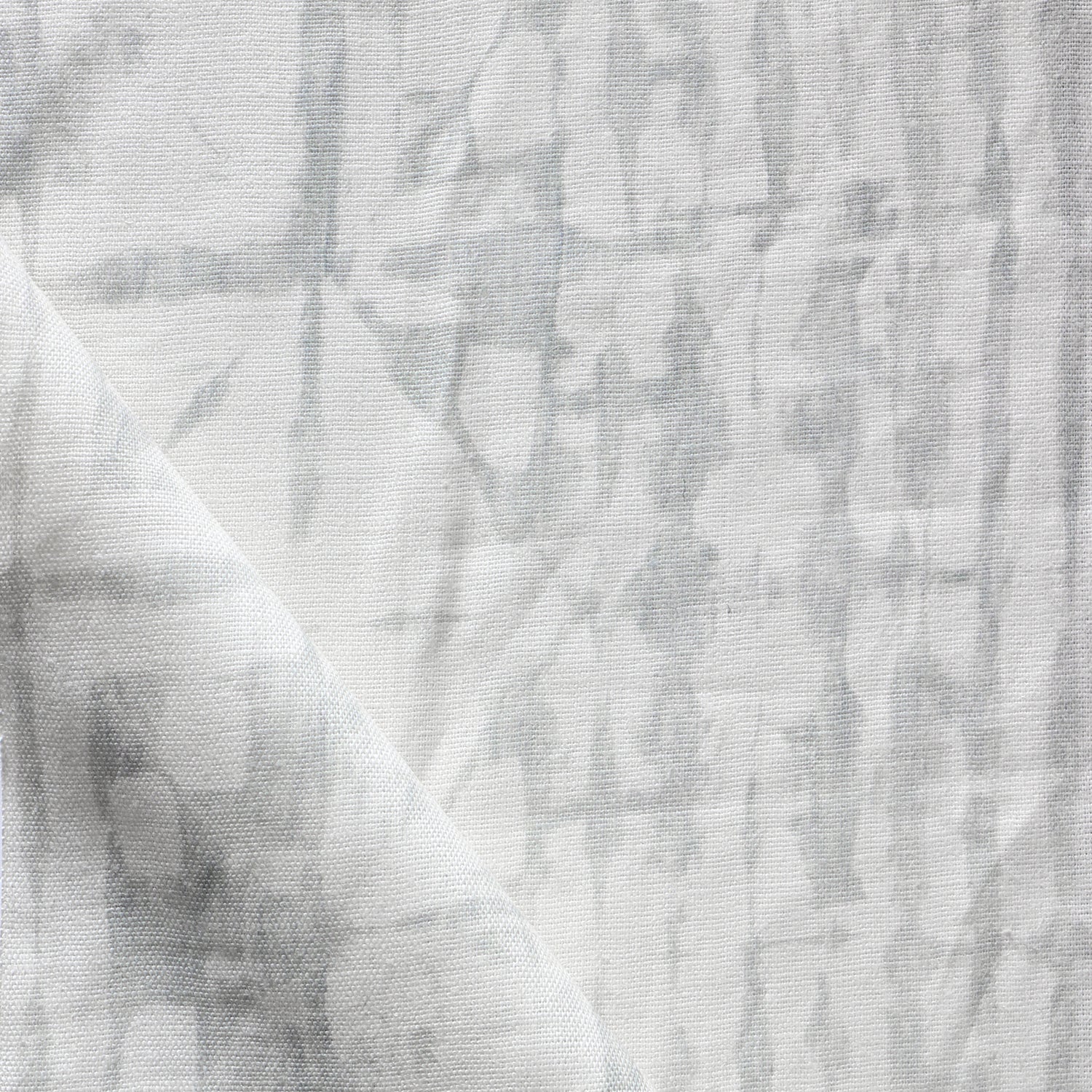 Detail of draped fabric in a watercolor dyed grid print in mottled white and gray.