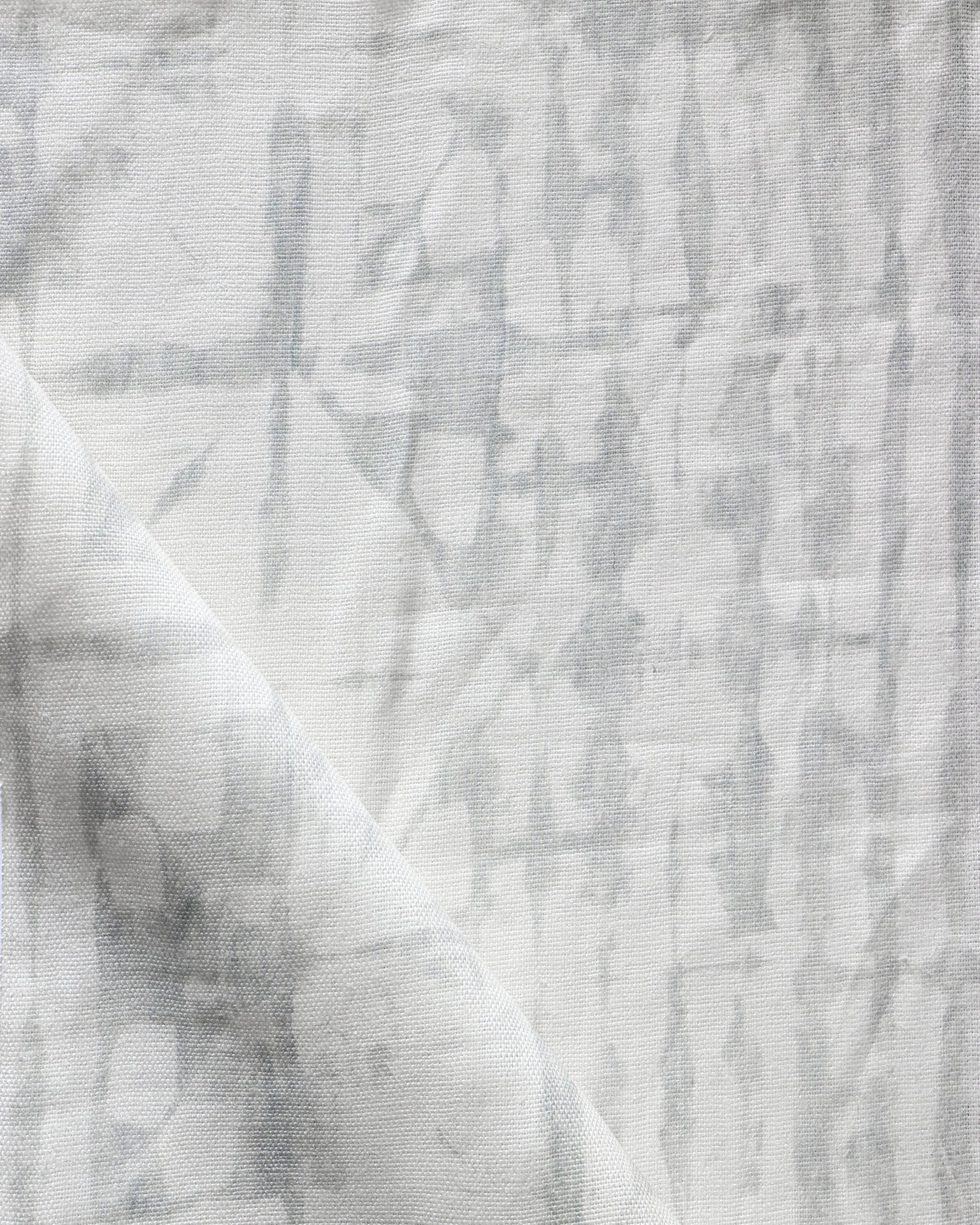 Detail of draped fabric in a watercolor dyed grid print in mottled white and gray.