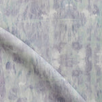 Detail of draped fabric in a watercolor dyed grid print in mottled purple and turquoise.