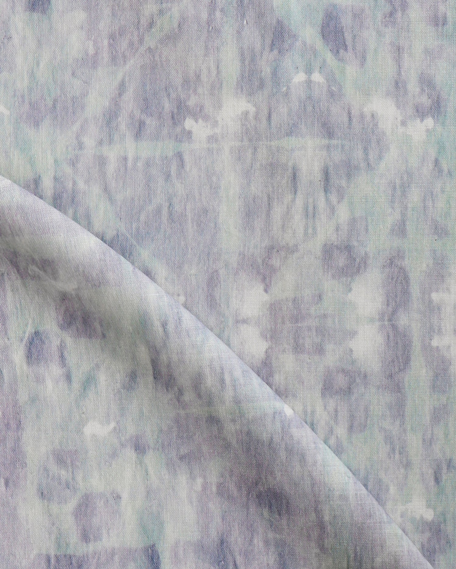 Detail of draped fabric in a watercolor dyed grid print in mottled purple and turquoise.