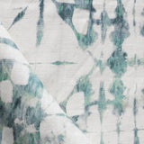 Detail of draped fabric in a watercolor dyed grid print in mottled white and green.