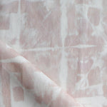 Detail of draped fabric in a watercolor dyed grid print in mottled white and pink.