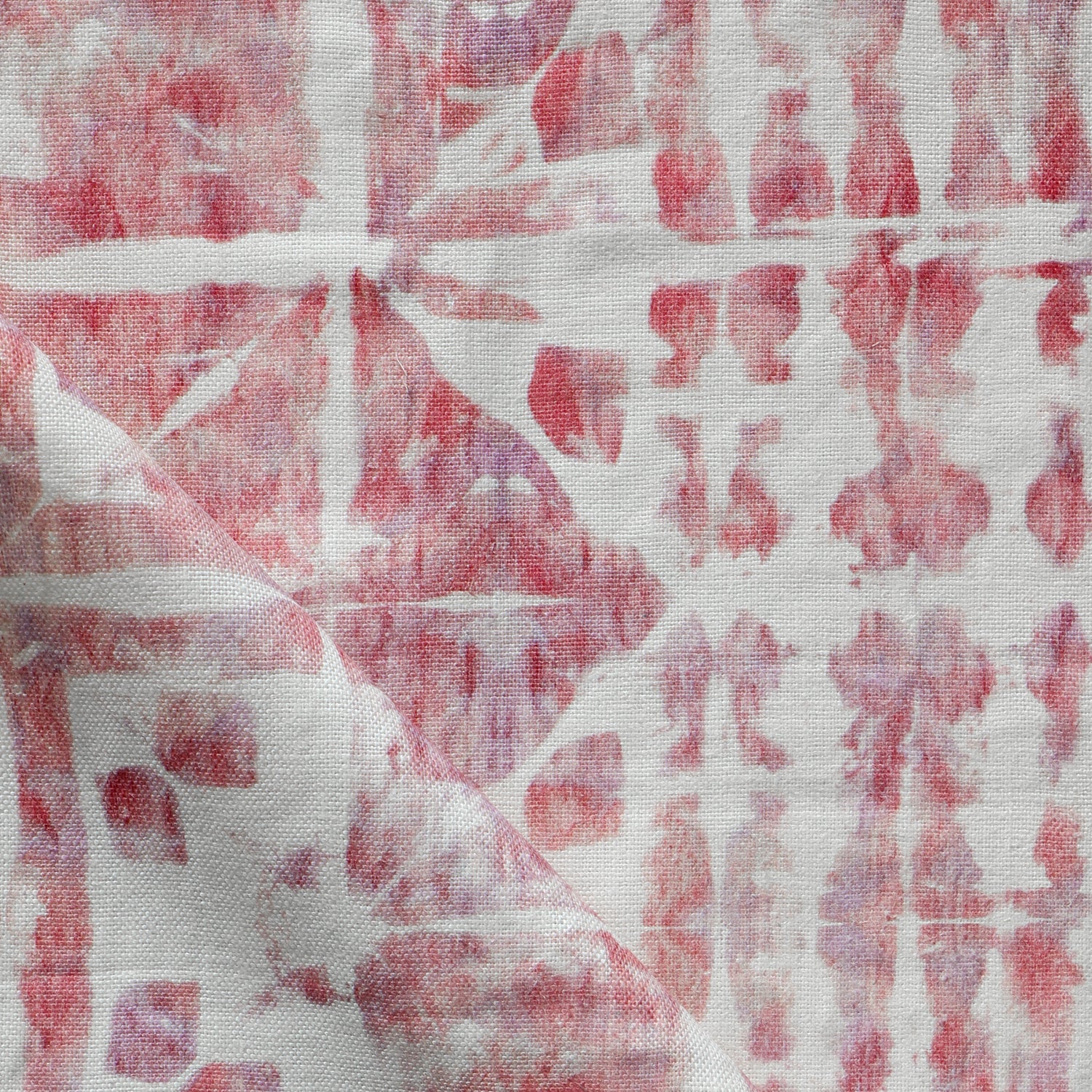 Detail of draped fabric in a watercolor dyed grid print in mottled white, pink and red.