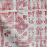 Detail of draped fabric in a watercolor dyed grid print in mottled white, pink and red.